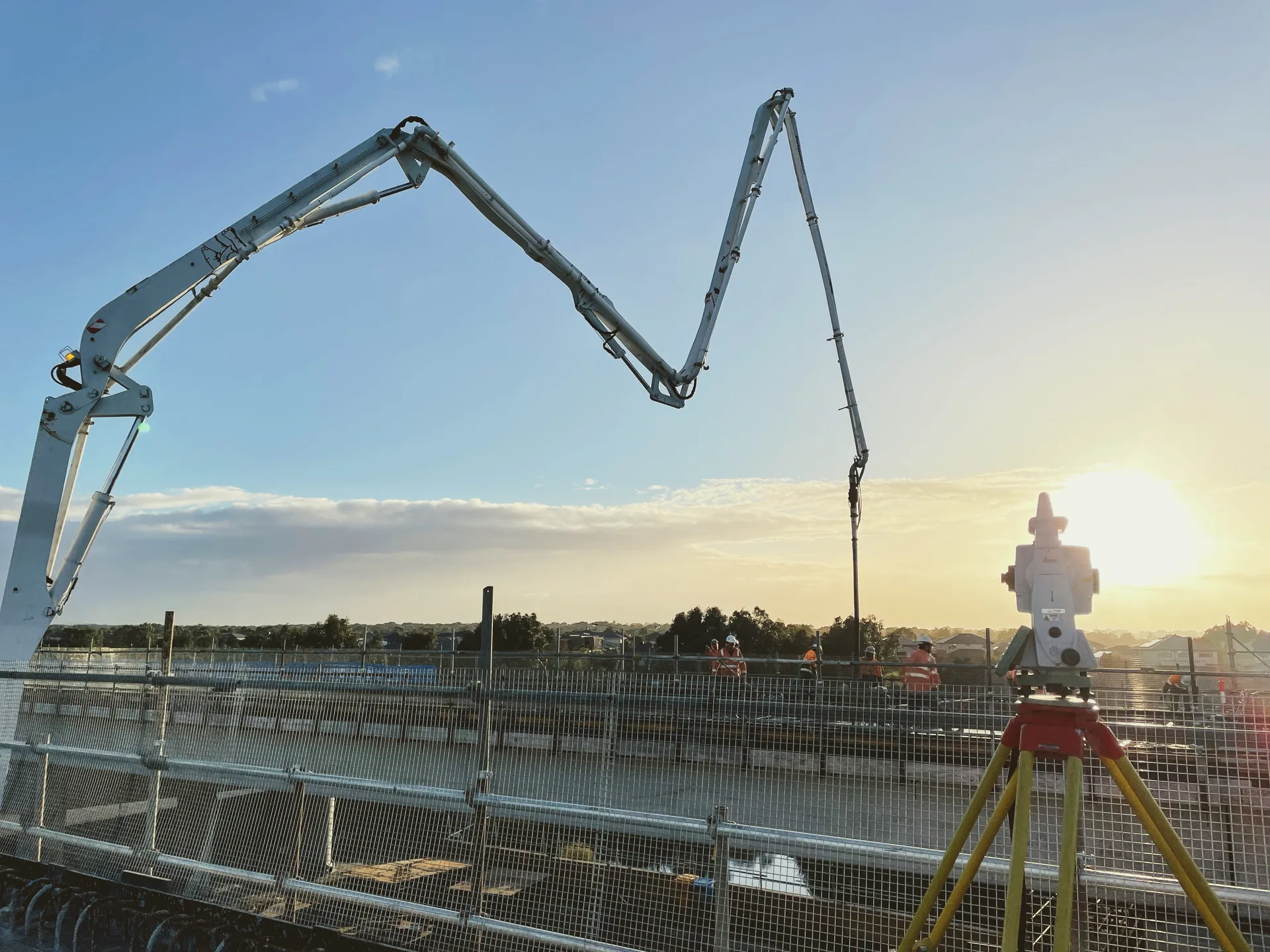 Concrete pump and survey setup at sunset